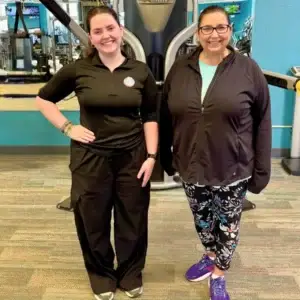 Personal trainer standing with female client inside gym.