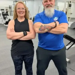 Older couple standing together inside personal training gym.